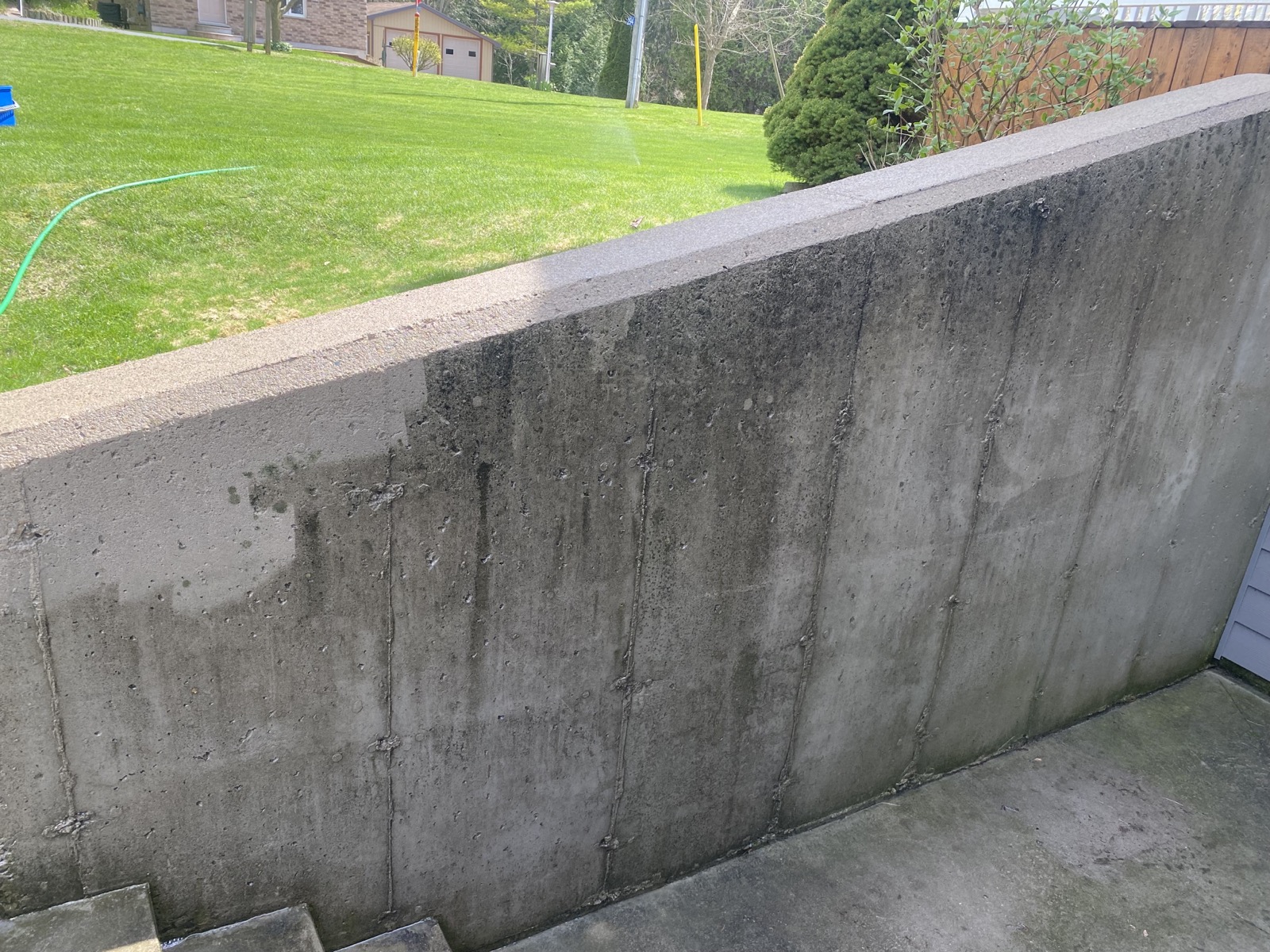 Streaked, stained concrete retaining wall before soft washing